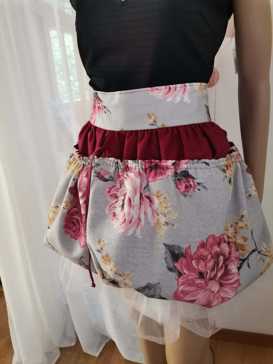 A close-up of an harvesting apron, featuring a light gray floral print with large pink and red roses