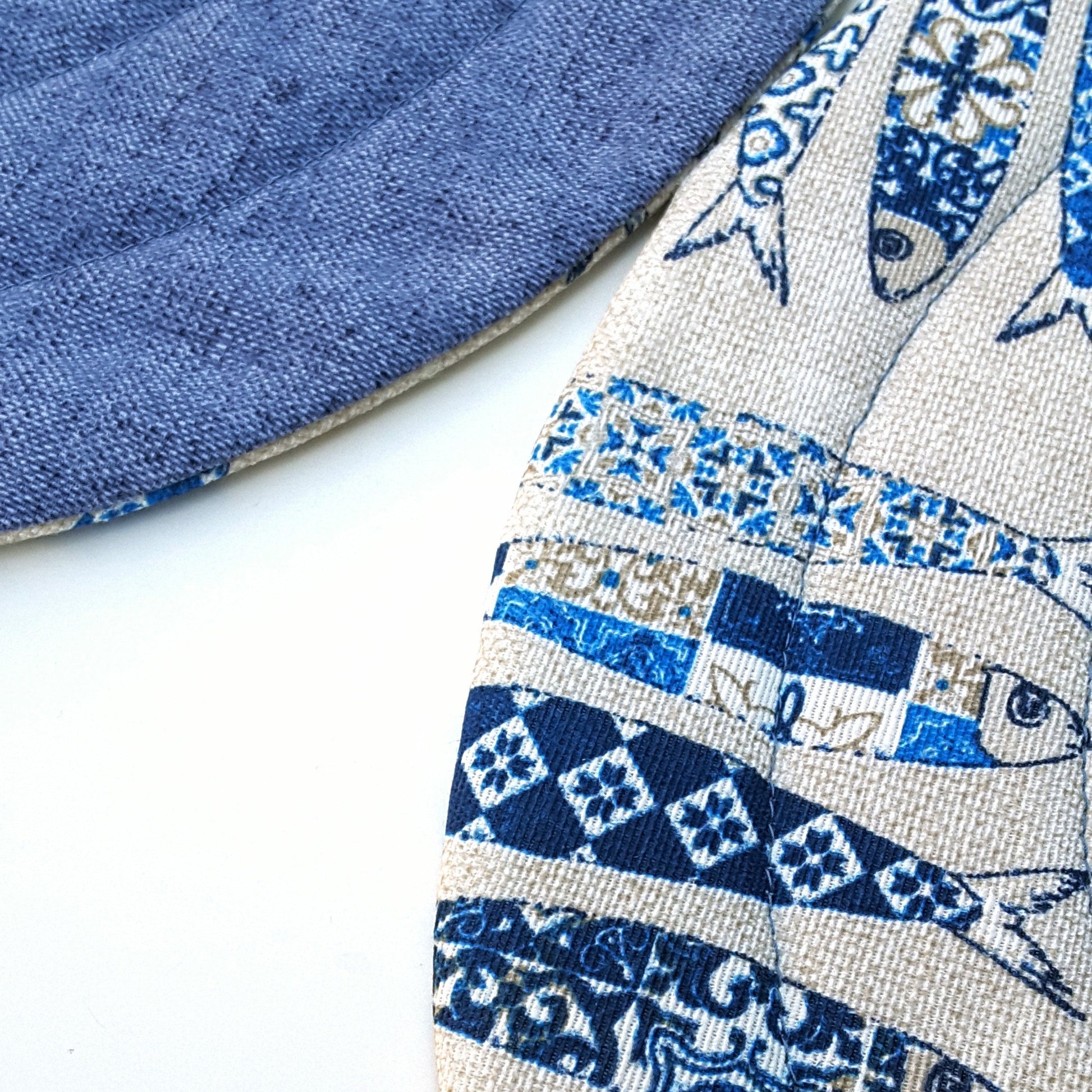A close up photo of around quilted placemat in sardines print, showing the fabric and print