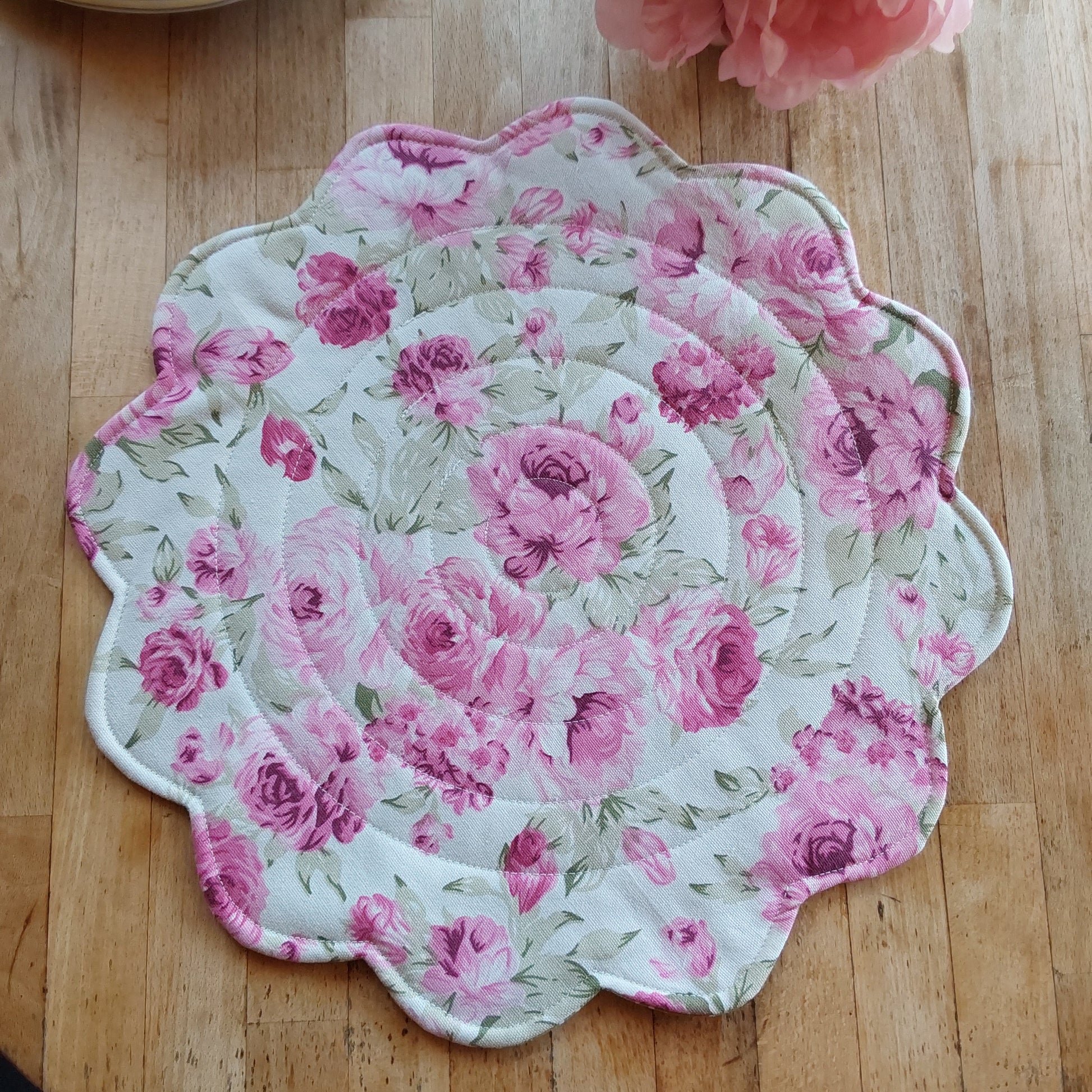 Round quilted placemat with scalloped edges in soft pink roses print