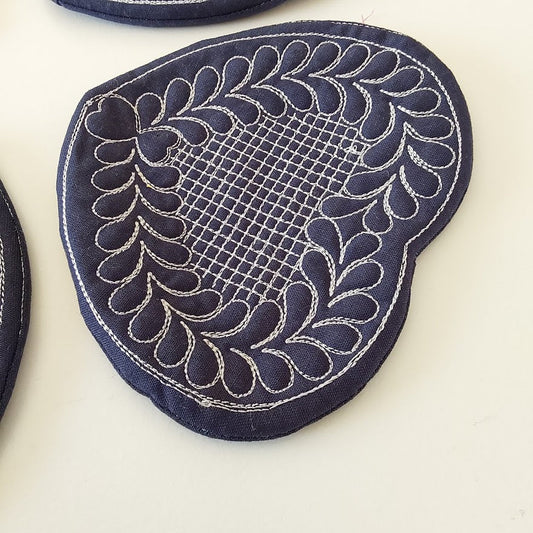 Navy blue fabric patch with intricate white embroidery on a light beige background