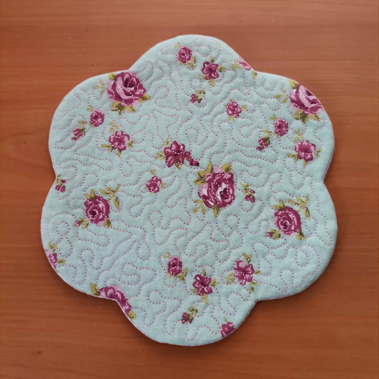 Floral-patterned quilted coaster on a wooden surface