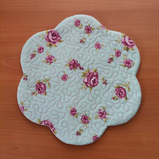 Floral-patterned quilted coaster on a wooden surface
