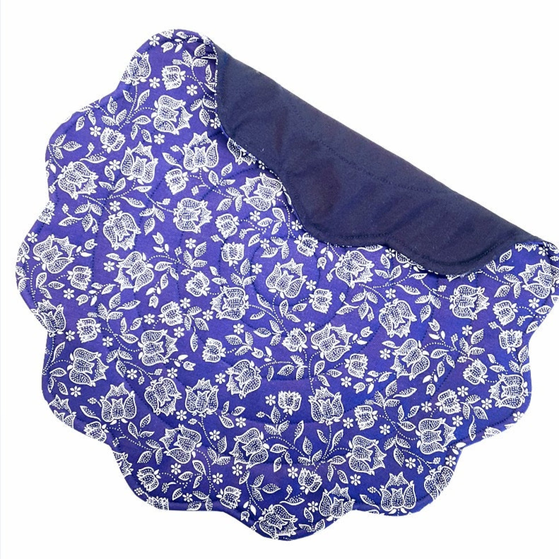Quilted blue round placemat with a floral pattern, white flowers on  blue, scalloped edges