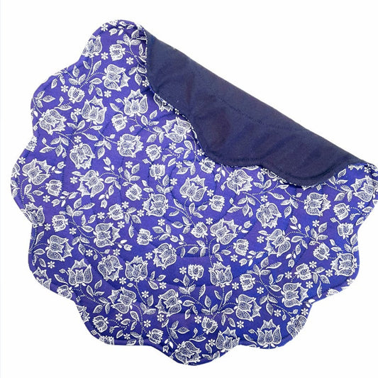 Quilted blue round placemat with a floral pattern, white flowers on  blue, scalloped edges
