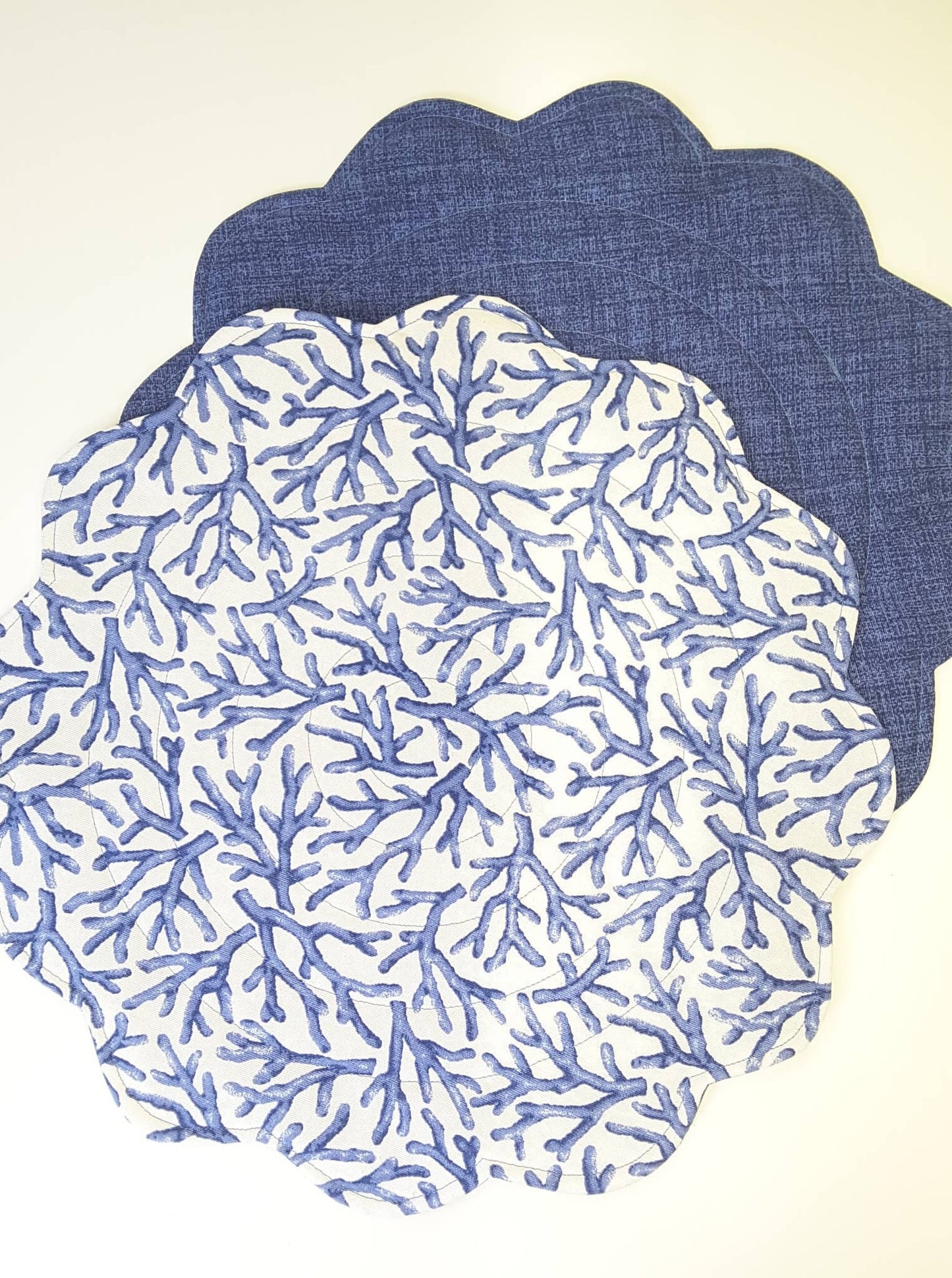 Round quilted placemats, top in blue corals on white and bottom in coordinating blue.