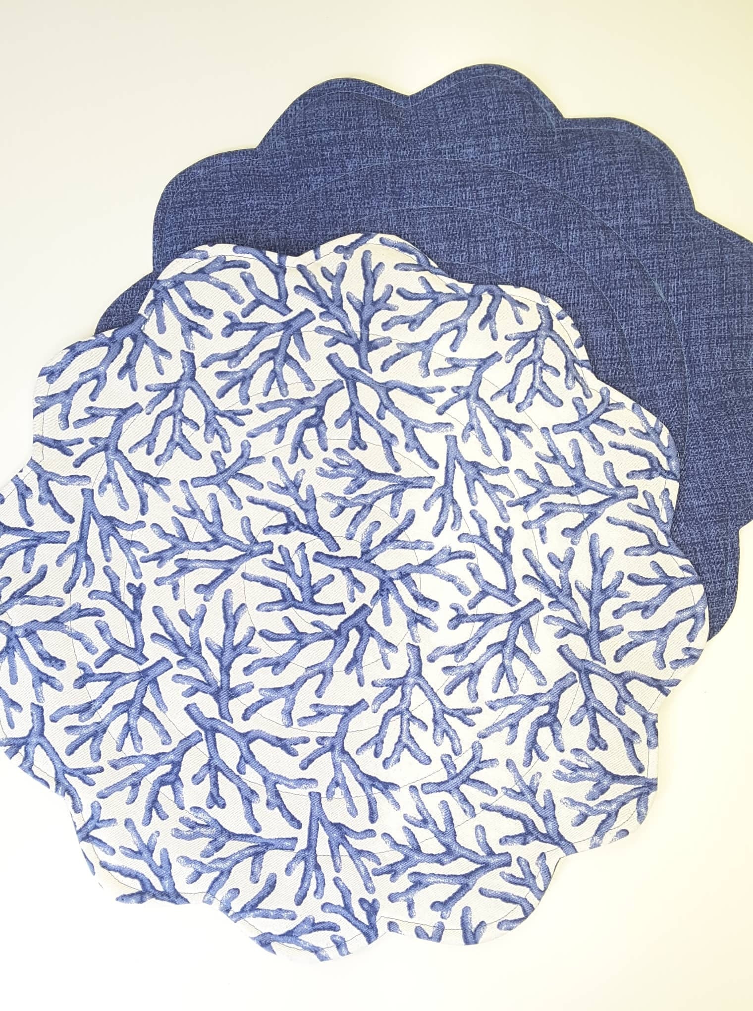 Round quilted placemats, top in blue corals on white and bottom in coordinating blue.
